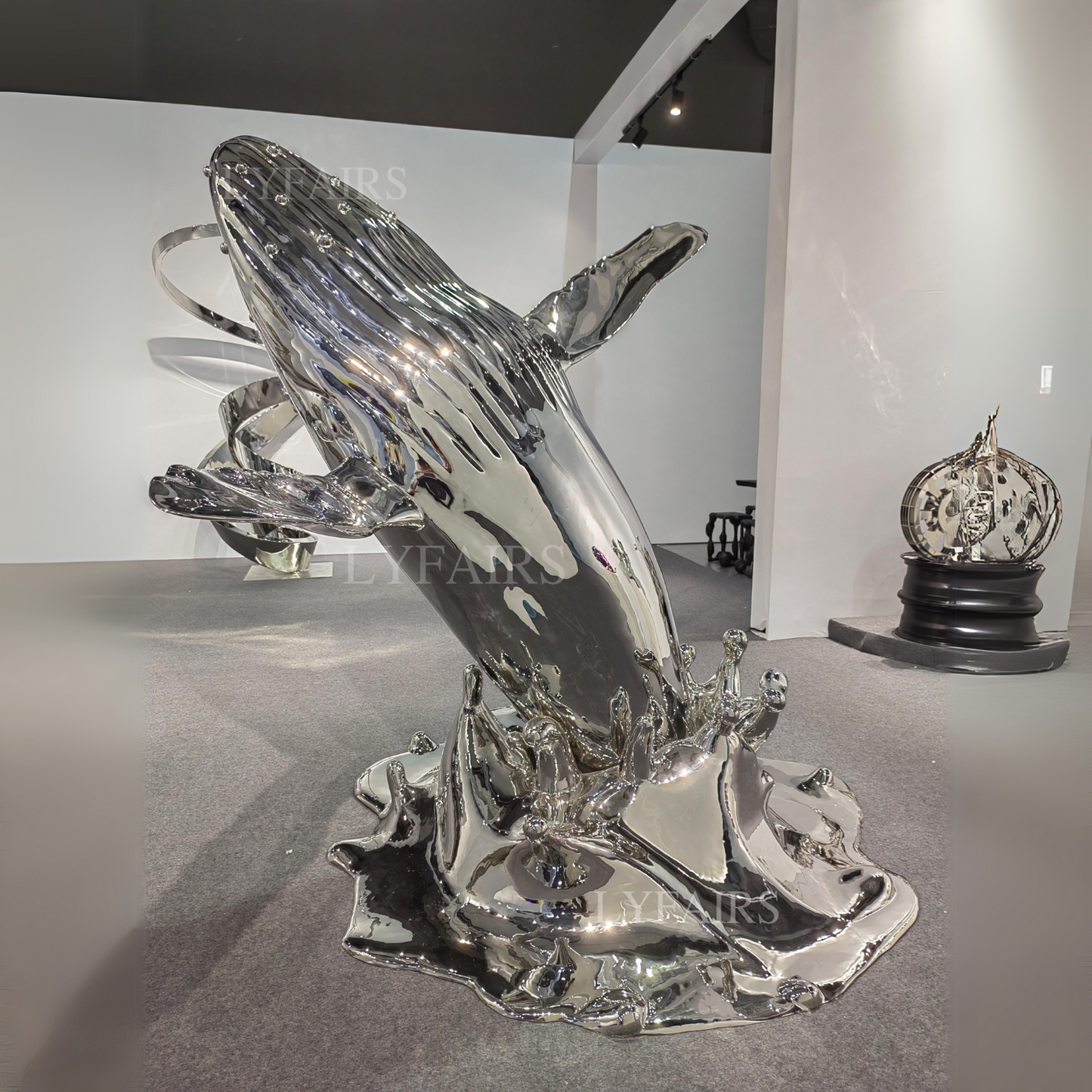 Une baleine gracieuse émergeant de l'océan dans une sculpture scintillante en acier inoxydable